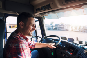 Happy truck driver maneuvering his truck in the parking lot of a truck stop