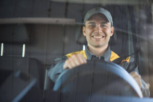 A man smiles as he sits behind the wheel of a big rig.