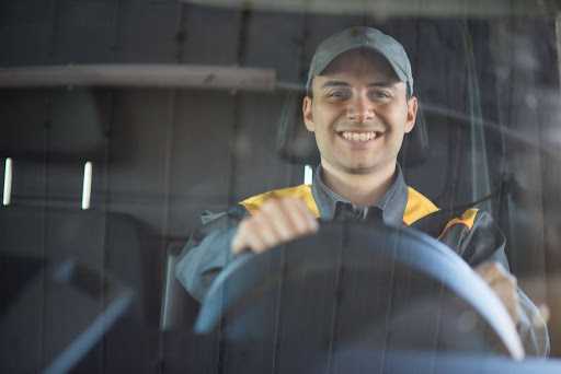 A man smiles as he sits behind the wheel of a big rig.